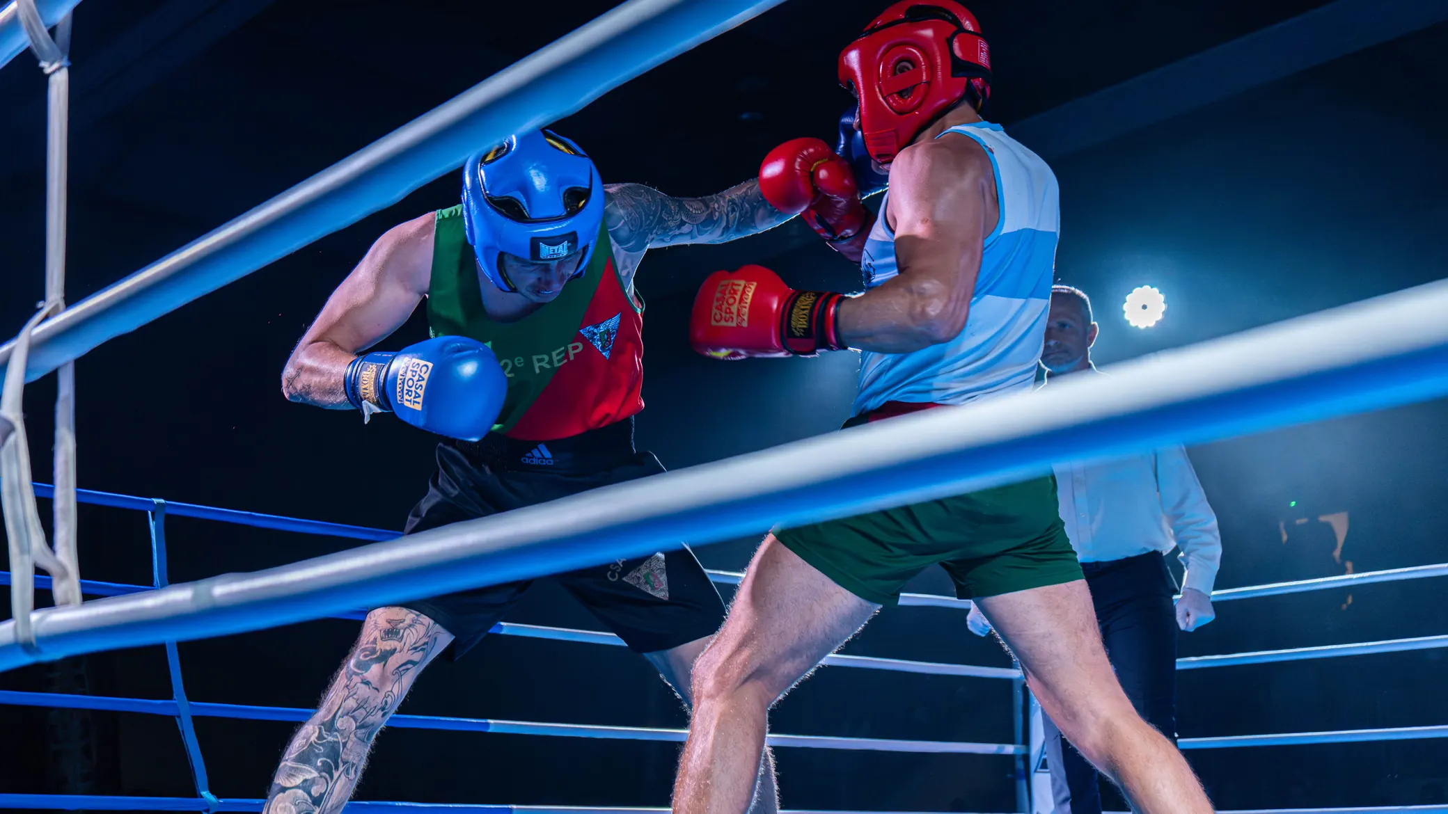 Corps à corps entre deux boxeurs sous les projecteurs, dont un combattant du 2e REP au casque bleu