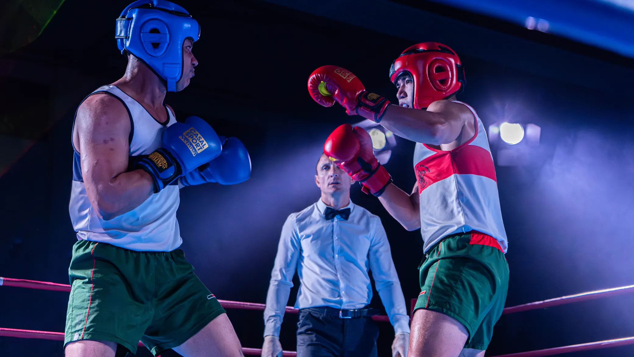 Deux boxeurs face à face de part et d’autre de l’arbitre, au centre du ring